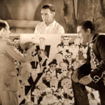 Here Frank Lloyd poses while caricaturist Xavier Cugat
(and band-leader for his daughter’s engagement party)
sketches his face with other Hollywood personalities;
notice bushy eyebrows. Richard Barthelmess, in costume
for current filming of “The Lash” (1930), looks on. Frank Lloyd poses while caricaturist Xavier Cugat